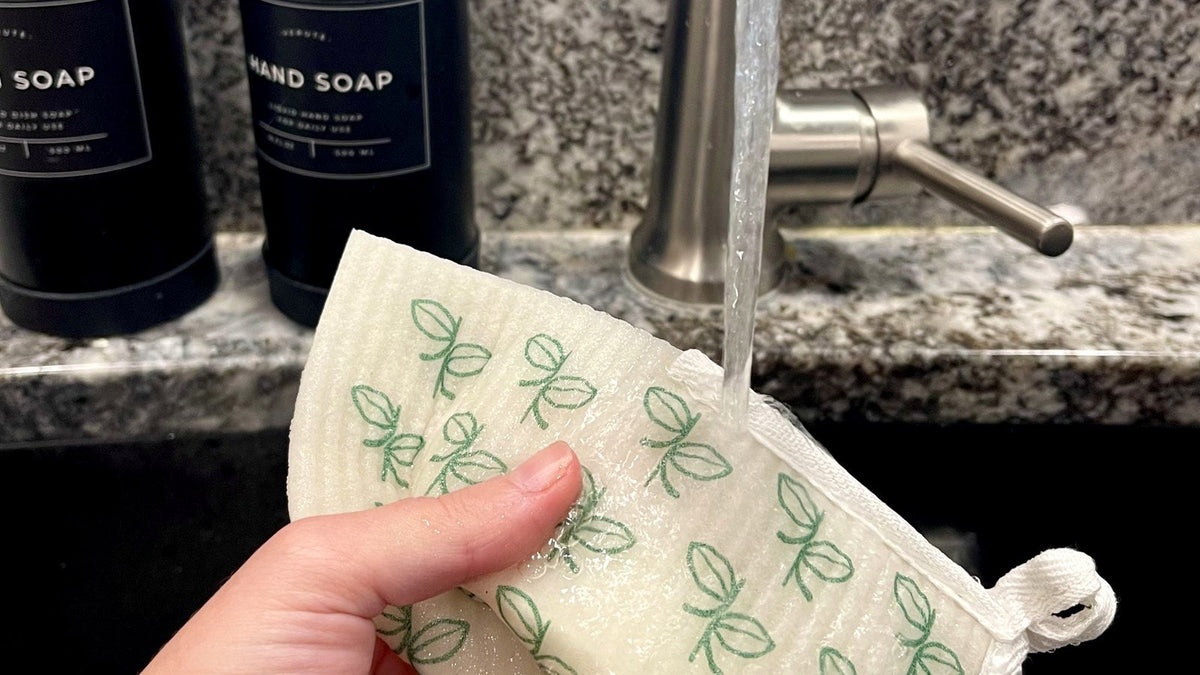 Rinsing a Swedish dishcloth under a running tap at the kitchen sink