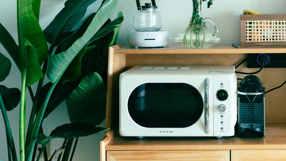 Retro white microwave on a wooden kitchen cabinet