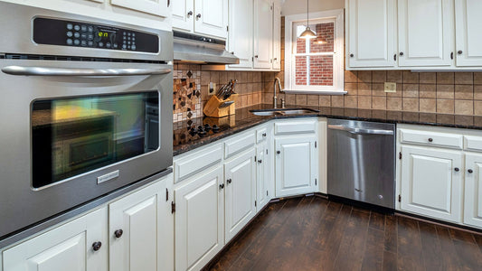Bright kitchen with white shaker cabinets, a stainless wall oven, range hood, and dark wood floors
