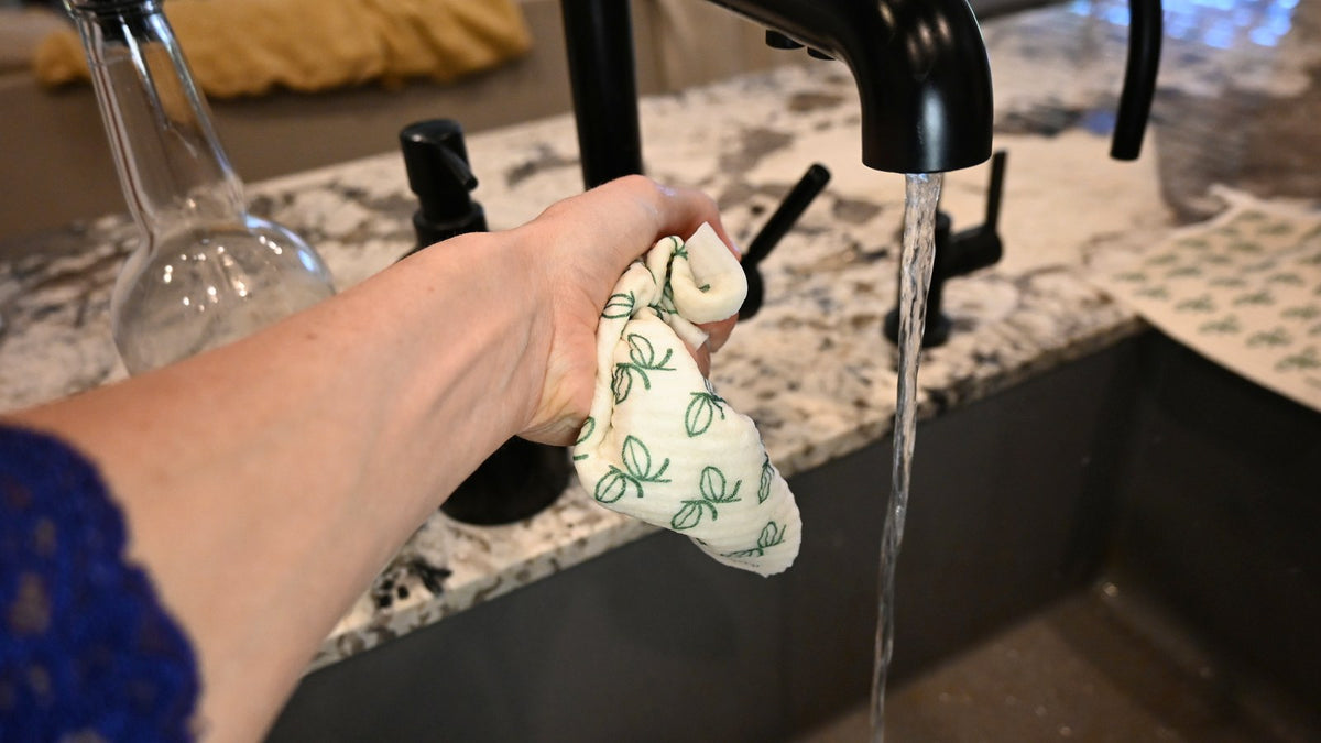 Wringing out a Swedish dishcloth under a running kitchen tap